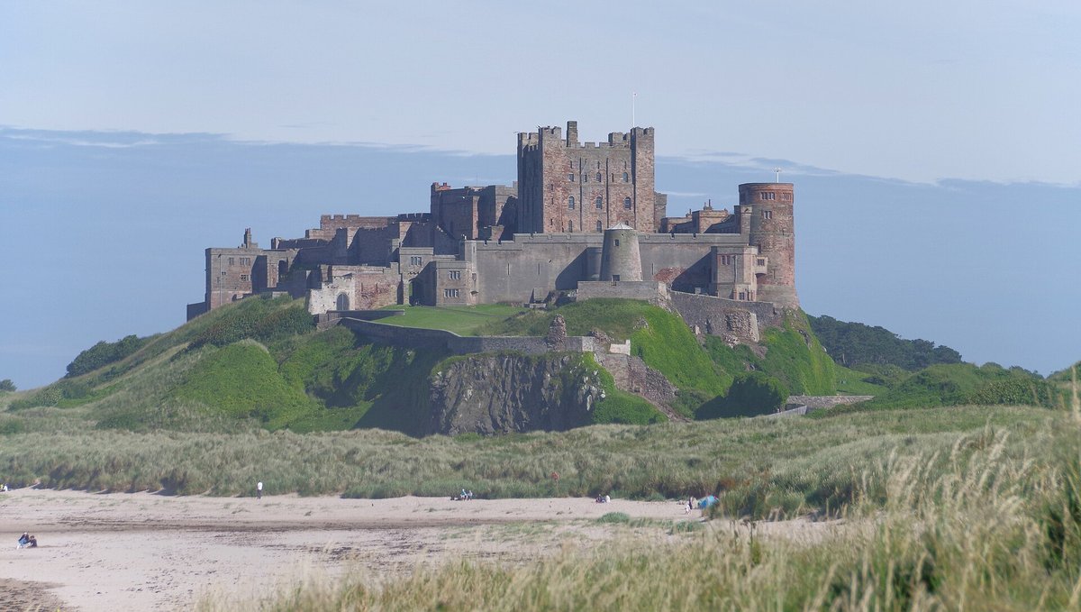 Bamburgh Castle on its green crag under a blue sky