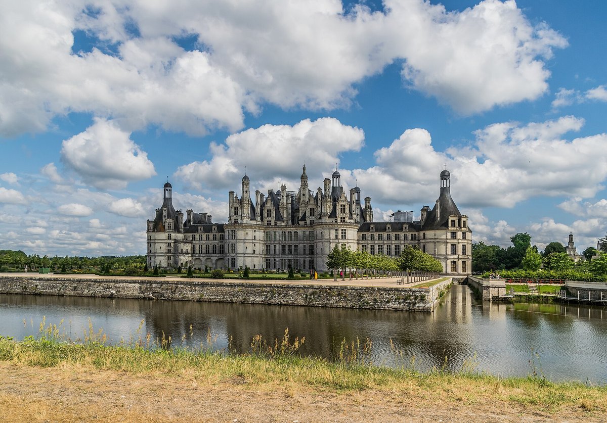The Château de Chambord reflected in water under a blue sky