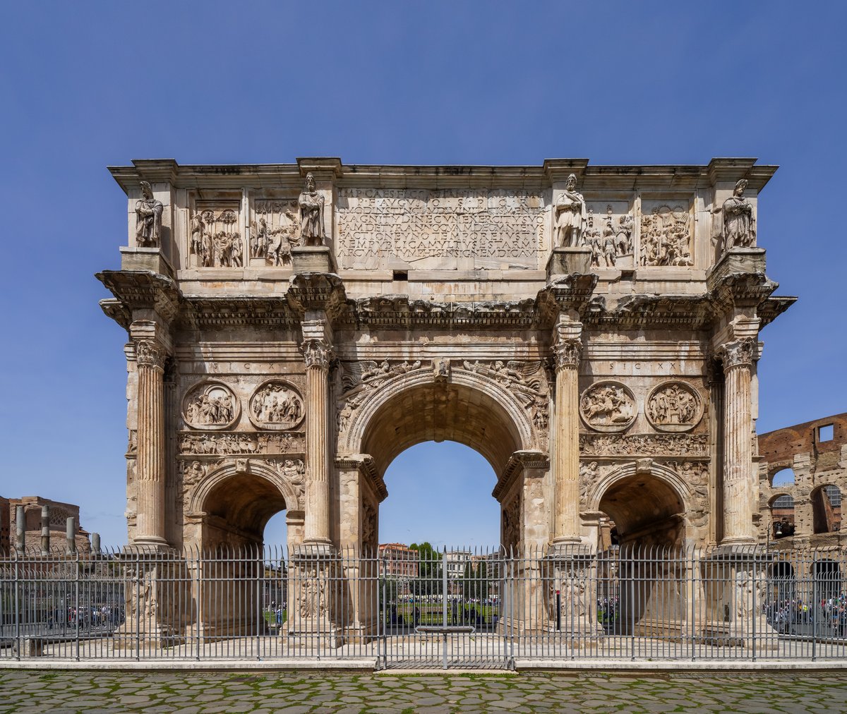 The Arch of Constantine in Rome, its three archways seen from the triumphal road with the Colosseum behind