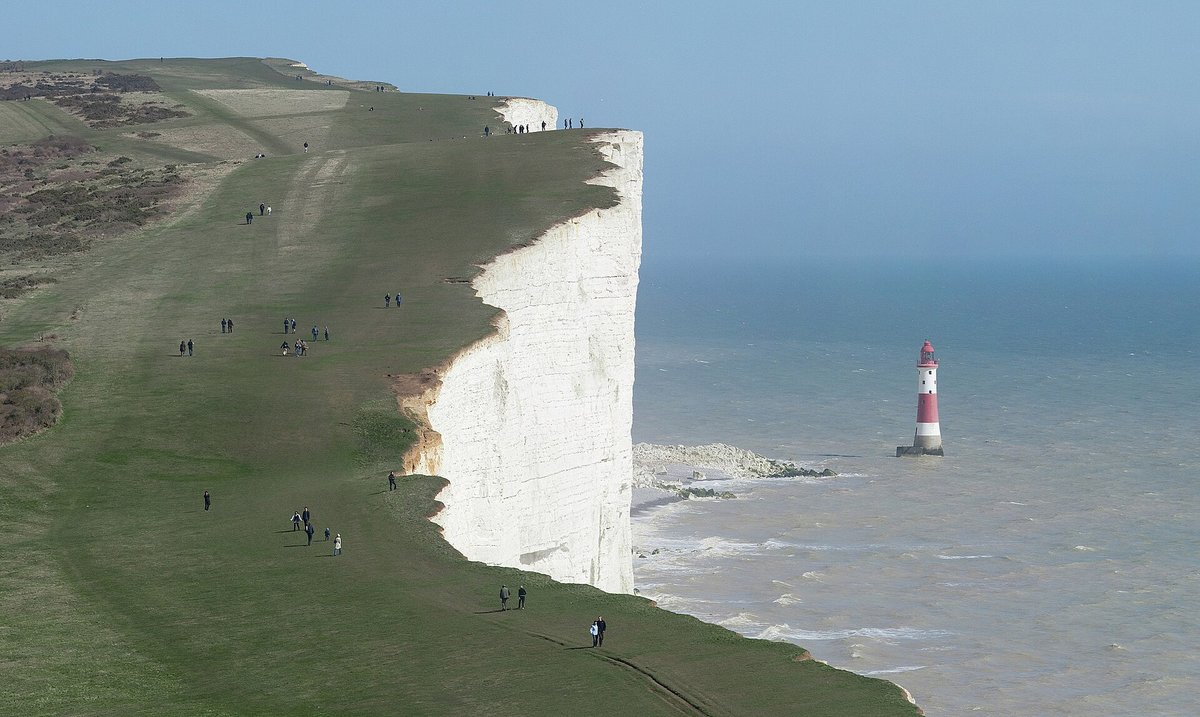 Beachy Head Lighthouse tiny beneath the white chalk cliffs
