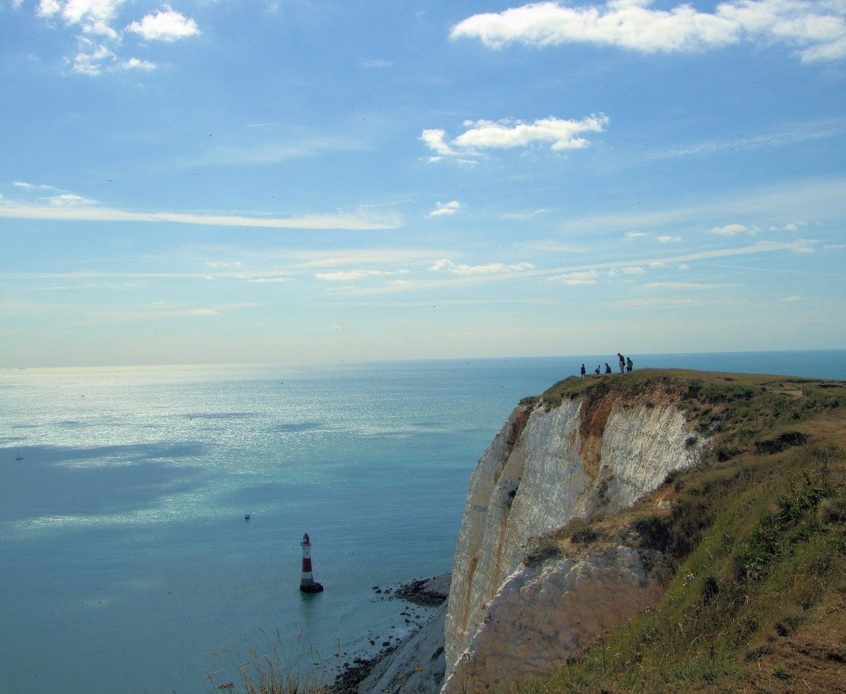 Beachy Head Lighthouse at the foot of the cliffs under a blue sky