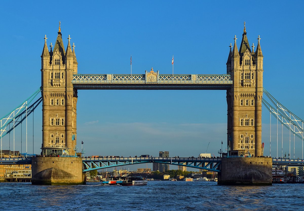 Tower Bridge from the river, its two towers under a blue sky