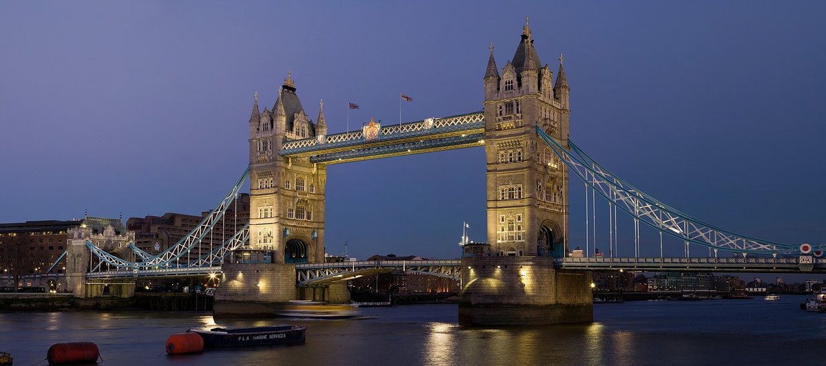 Tower Bridge floodlit at dusk, reflected in the Thames