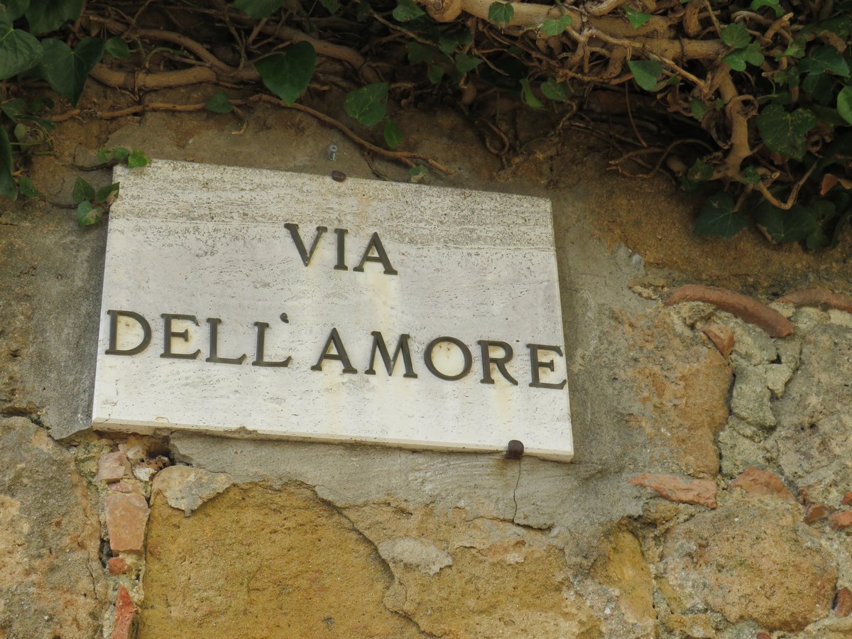 The street sign of the Via dell'Amore in Pienza, on a wall of weathered stone